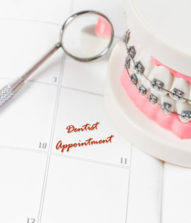Tooth model with braces sitting on top of calendar