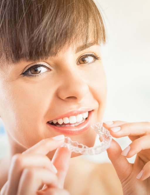 Young woman holding a Clear Correct clear aligner in Houston