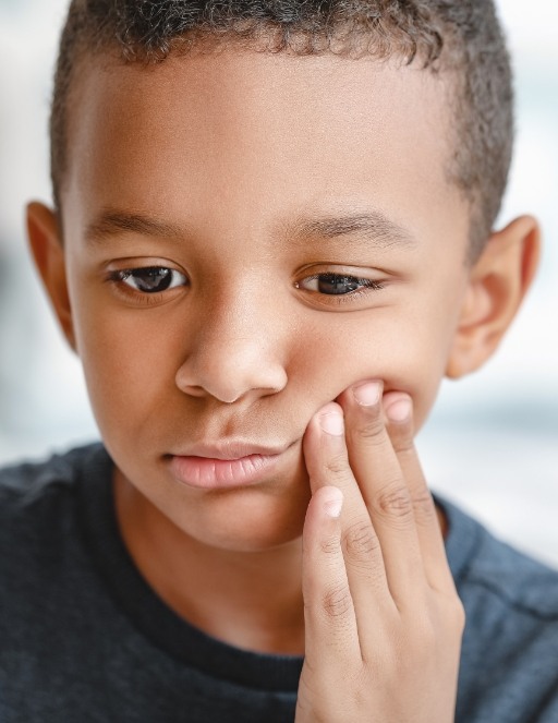 Boy holding his cheek in pain needing emergency orthodontist in Houston