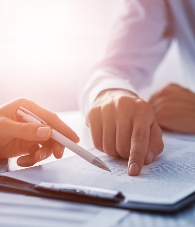 Person pointing to paperwork with another person across desk