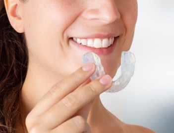 woman holding cheek in pain
