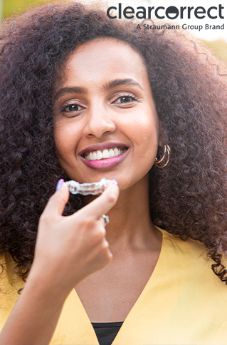 Smiling woman holding a clear aligner