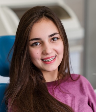 Teenage girl with braces sitting in dental chair