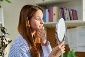 Woman looking in mirror, concerned about shifting teeth