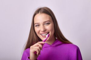 Young woman with braces holding toothbrush