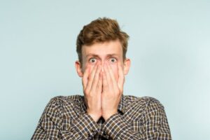 Shocked young man covering his mouth