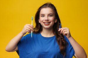 Young woman with braces holding toothbrush and interdental brush