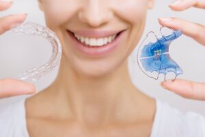 Woman holding a clear retainer and a Hawley retainer
